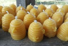 several bees are lined up in rows on a wooden table with white candles attached to them