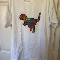 White T-Shirt, New Without Tags. Could Use An Iron But Otherwise In New Condition. T-Shirt Is White With Multicolored Dinosaur On The Front. White Dinosaur Print T-shirt For Summer, White Short Sleeve Tops With Dinosaur Print, Short Sleeve White Tops With Dinosaur Print, White Short Sleeve Top With Dinosaur Print, Coach Cotton Crew Neck Tops, Casual Coach Crew Neck Tops, Coach Tshirts, Coach Shirts, White T Shirt