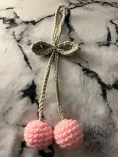 two pink crocheted balls tied together on a black and white cloth with a bow