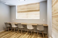 a row of white chairs sitting in front of a wooden table next to a window