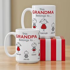 two coffee mugs sitting next to each other on top of a wooden table in front of a red and white gift box