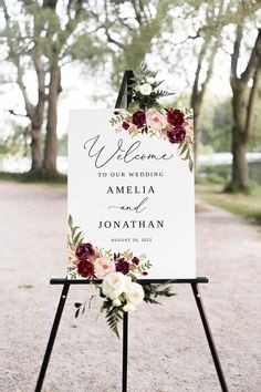 a welcome sign with flowers and greenery on it