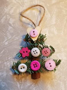 a christmas tree made out of buttons and pine needles on a white tablecloth background