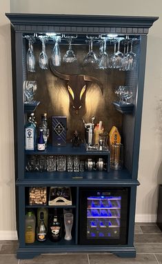 a blue bar with wine glasses and liquor bottles on the top shelf in front of it