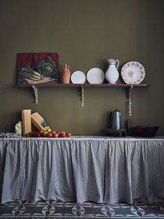 a table topped with plates and bowls next to a shelf filled with other items on top of it