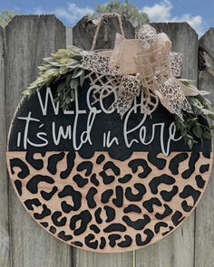 a wooden sign that says welcome to it's wild in love with a leopard print