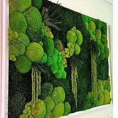 moss covered wall hanging on the side of a building with trees and plants in it