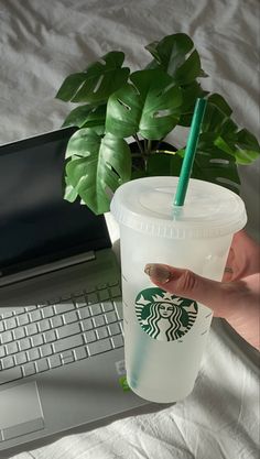 a hand holding a starbucks cup next to a laptop