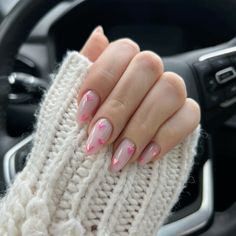 a woman's hand with pink and white manies on her nails sitting in a car