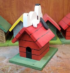 three wooden birdhouses with different colors and designs on them, one red the other green