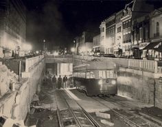 an old black and white photo of a train on the tracks in a city at night