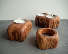 three wooden candle holders with white candles in them sitting on a table next to each other