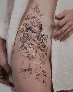 a woman's thigh with an owl and flowers tattoo on it