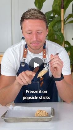 a man in an apron is eating food on a plate with the words freeze it on popsicle sticks