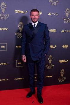 a man in a suit and tie standing on a red carpet at an event with the ballon d'or logo behind him