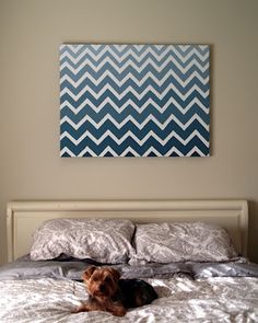 a dog laying on top of a bed in a bedroom next to a wall hanging