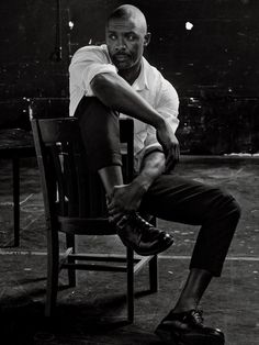 a black and white photo of a man sitting in a chair with his legs crossed