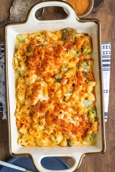 a casserole dish with broccoli and cheese in it on a wooden table