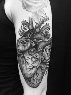 a black and white photo of a heart tattoo on the right arm, with flowers in it