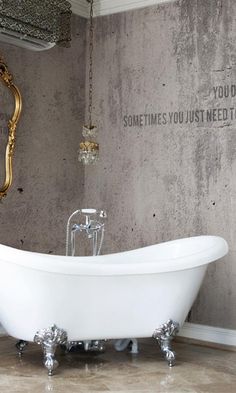 an old fashioned claw foot bathtub in a bathroom with concrete walls and flooring