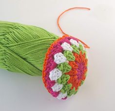 a ball of yarn sitting on top of a white table next to a green leaf