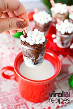 someone is dipping marshmallows into a cup of hot chocolate with candy canes