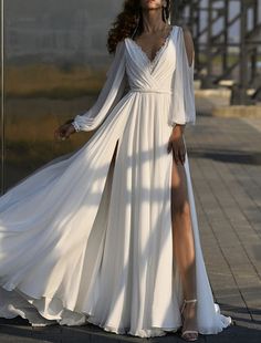 a woman in a white dress is standing on the sidewalk