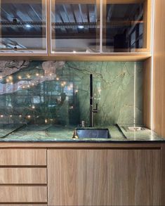 a kitchen with marble counter tops and wooden cabinetry, along with glass shelves above the sink