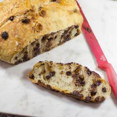 a loaf of bread sitting on top of a white counter next to a red knife