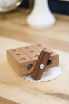 a wooden block with holes on it sitting on a table next to a small clock