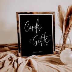 a sign that says cards and gifts next to a vase with feathers