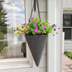 a hanging planter with flowers in it on the side of a house's front door