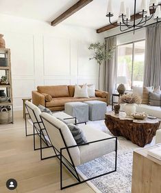 a living room filled with furniture and a chandelier hanging from the ceiling in front of a window