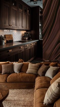 a living room filled with brown furniture and lots of wooden cabinetry next to a kitchen