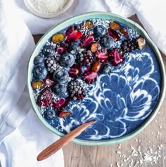 a bowl filled with blueberries, raspberries and oats on top of a wooden table