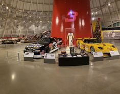 several cars are on display in a large room