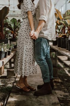 an engaged couple holding hands in a greenhouse