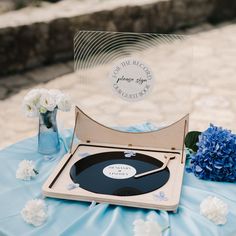 a record player sitting on top of a table next to blue flowers and vases