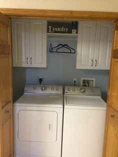 a washer and dryer in a small room with white cabinets on the wall