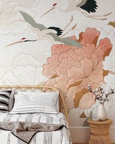 a bed sitting next to a wall with flowers and birds painted on the wall behind it