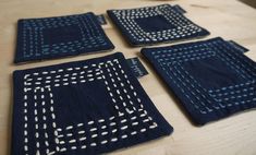 four pieces of blue cloth with white stitching on them sitting on a wooden table