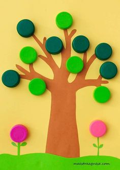 a paper cutout of a tree with green and pink circles on the leaves, in front of a yellow background