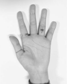 a palm tree tattoo on the middle of someone's left hand, with two fingers