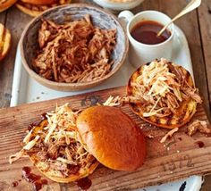 pulled pork sandwiches with bbq sauce and coleslaw on a wooden cutting board