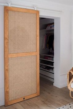 an open closet with wicker doors in a white walled room next to a rattan chair