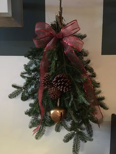 a christmas tree hanging from the side of a wall with a red bow on it