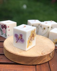 some white cubes with flowers on them sitting on a wooden table in front of grass