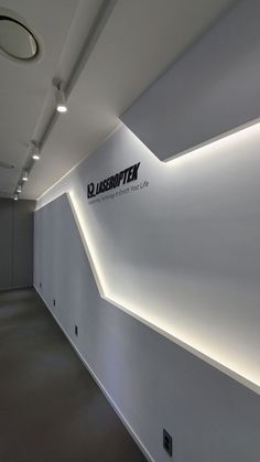 the interior of an office building with white walls and lights on either side of the wall