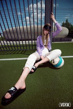 a woman sitting on the ground with a soccer ball in her hand and wearing sunglasses