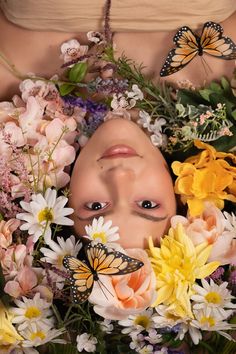 a woman is surrounded by flowers and butterflies